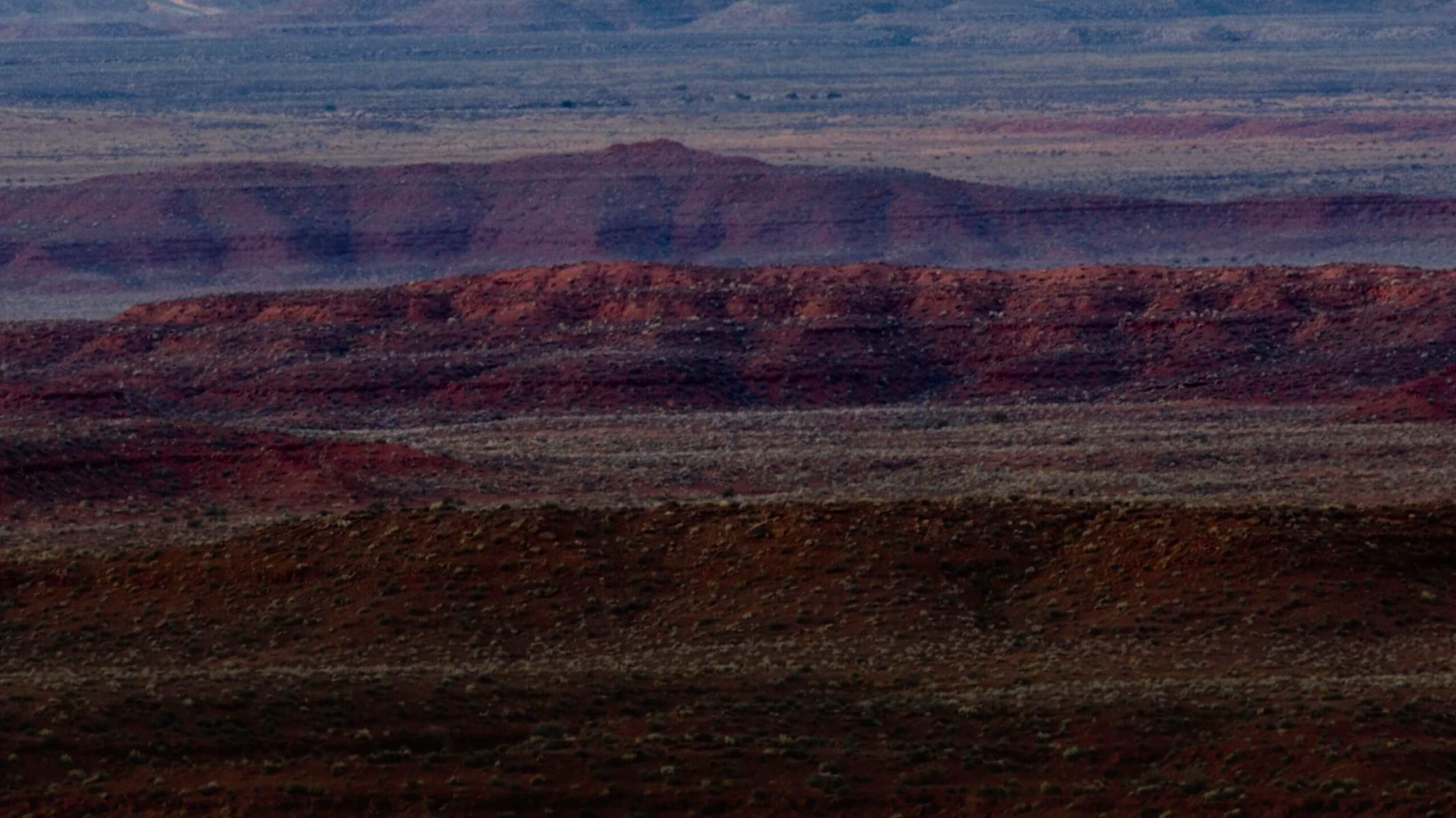 A Trail Mix protein bar is pictured in front of a mountain range is which has been treated with a blue-ish color..